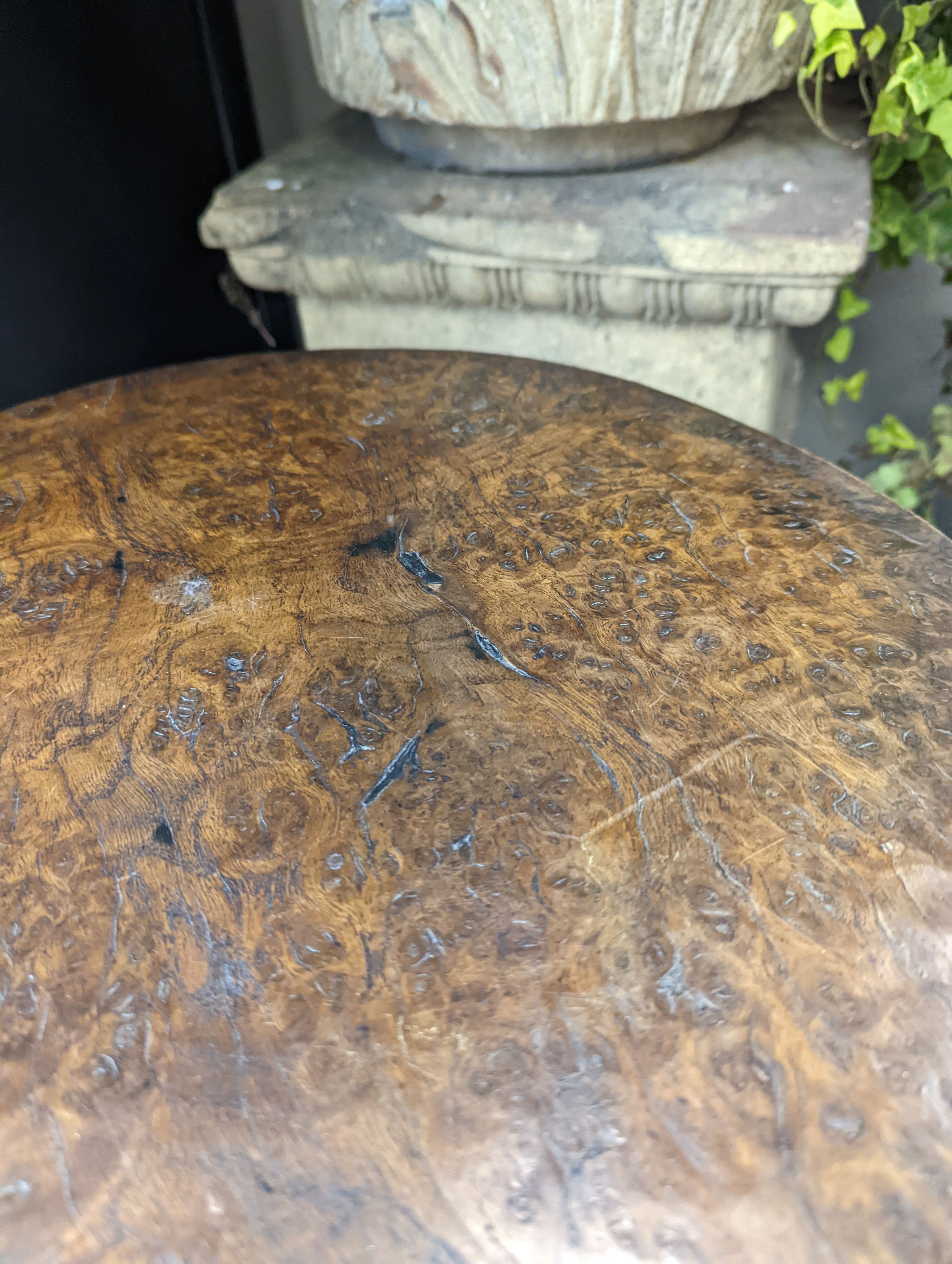 A circular burr elm and ash primitive cricket table with T shaped stretcher, diameter 44cm, height 61cm